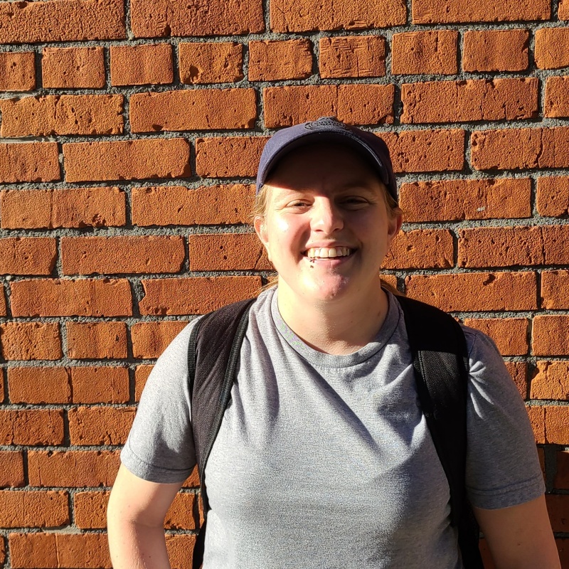 Holly standing in front of a brick wall with an open smile