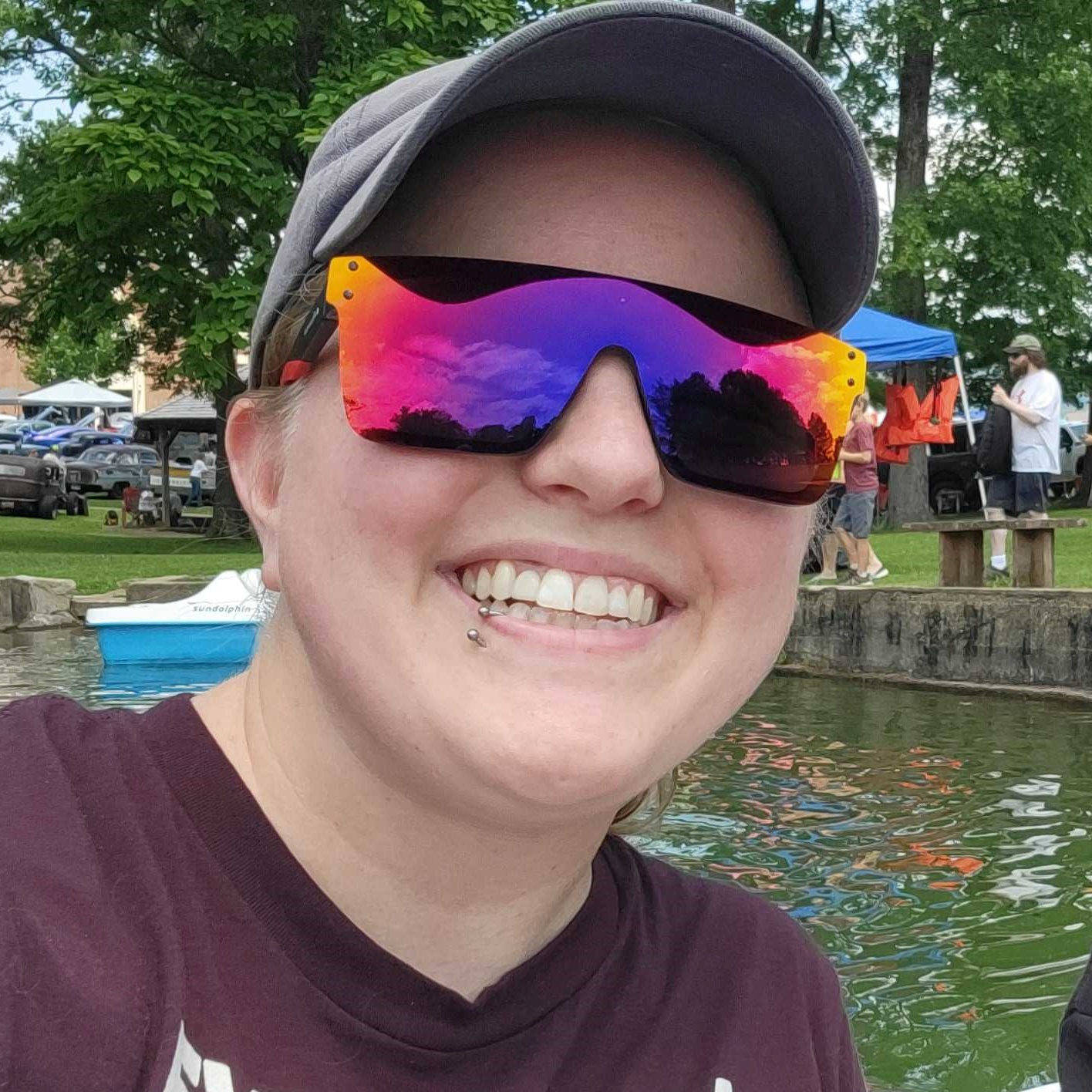 Holly wearing red-purple sunglasses while on a boat in a pond
