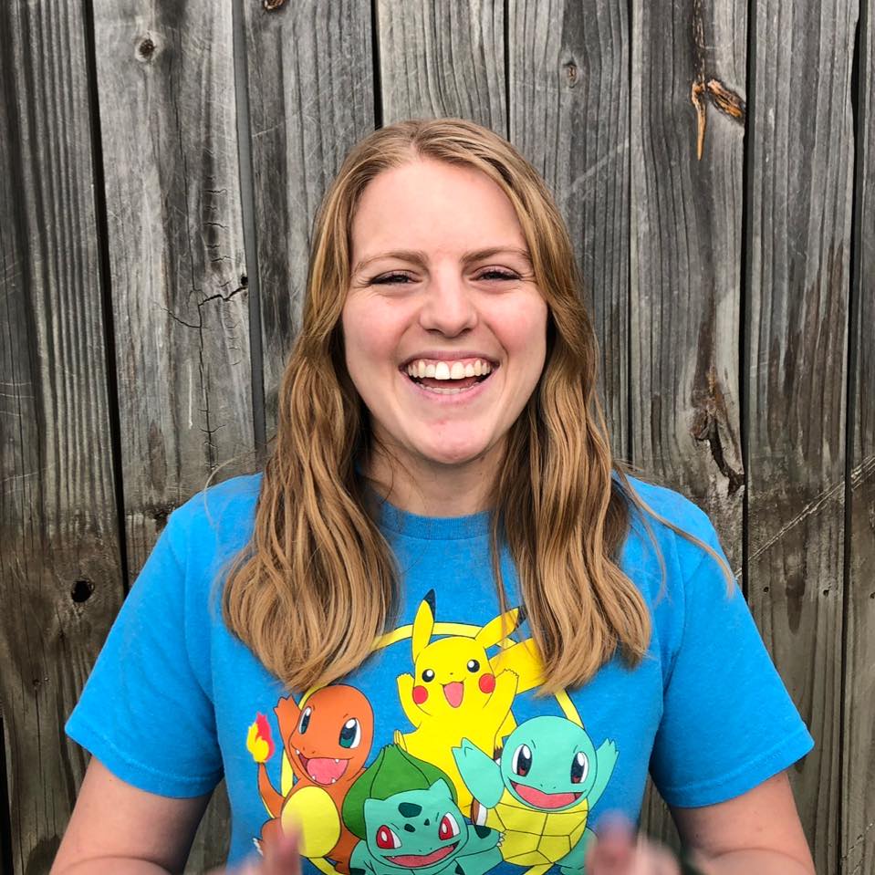 Holly wearing a Pokemon t-shirt standing in front of a fence with an open smile